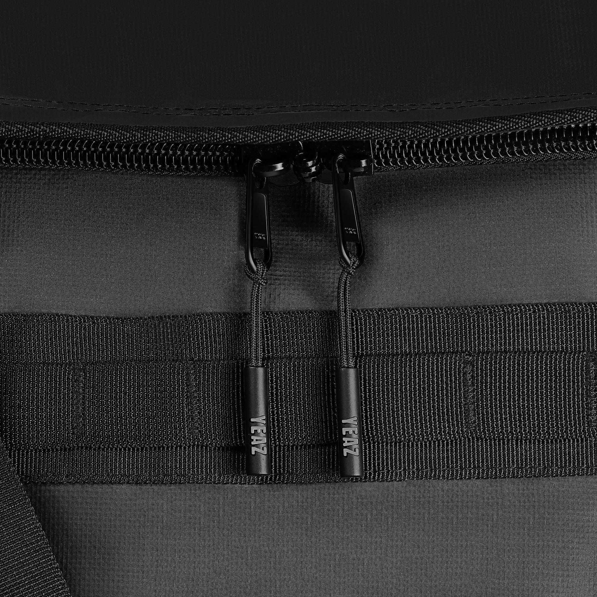 Primo piano di due cerniere su una borsa sportiva nera. I cursori hanno la scritta YEAZ.
