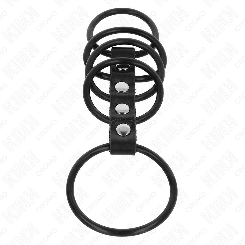 Anelli per pene neri in silicone, collegati da una cinghia in pelle con tre rivetti. Su sfondo bianco.