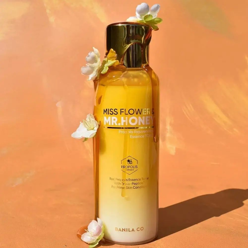 Flacone giallo trasparente con tappo dorato. Scritta: Miss Flower & Mr. Honey. Decorato con fiori bianchi.