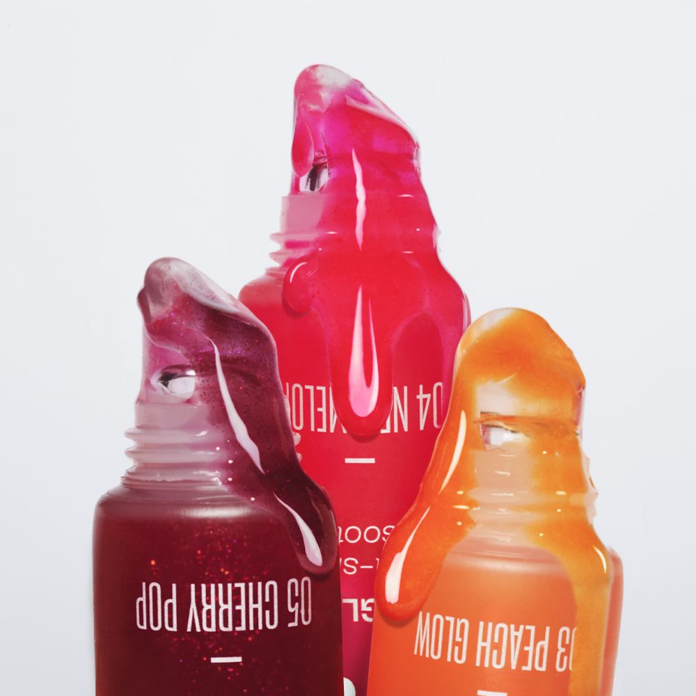 Tre tubi di lucidalabbra con contenuto che fuoriesce. Colori: 05 Cherry Pop, 04 Neo-Melon, 03 Peach Glow.