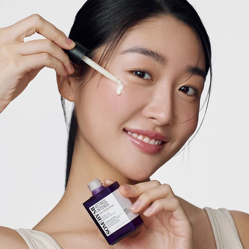 Donna che applica il siero sul viso. Flacone: Retinol Intense Reactivating Serum. Marchio: SOMEBYMI.