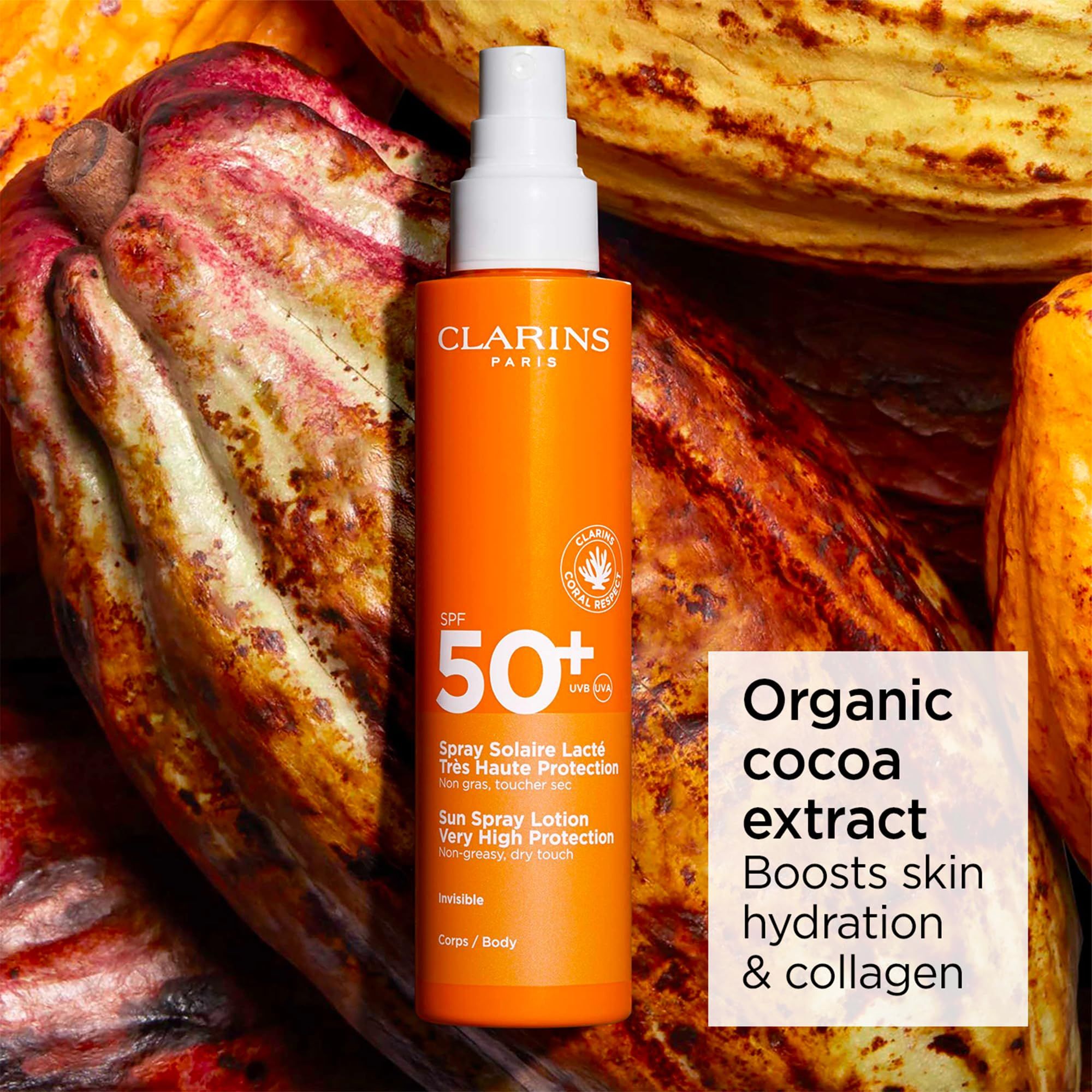 Flacone spray arancione con erogatore bianco. Testo: Clarins, SPF 50+, Sun Spray Lotion. Protezione molto alta. Sfondo: fave di cacao.