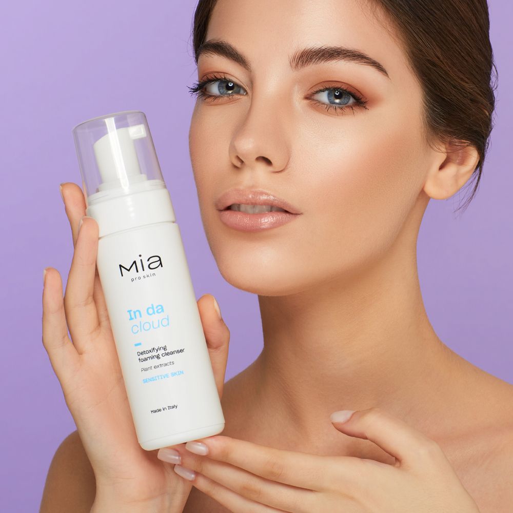 Donna tiene Mia Pro Skin In da Cloud. Flacone bianco, tappo a pompa. Testo: Detoxifying Foaming Cleanser. Per pelli sensibili.