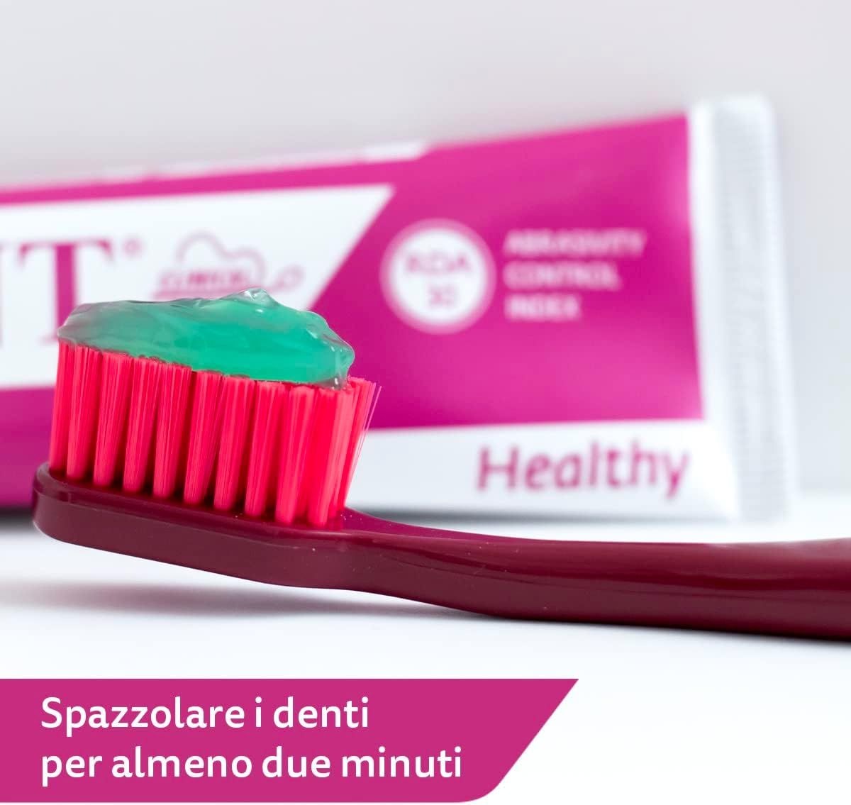 Spazzolino con dentifricio. Dentifricio verde. Spazzolino rosso. Tubo sullo sfondo. Testo: Spazzolare i denti per almeno due minuti.