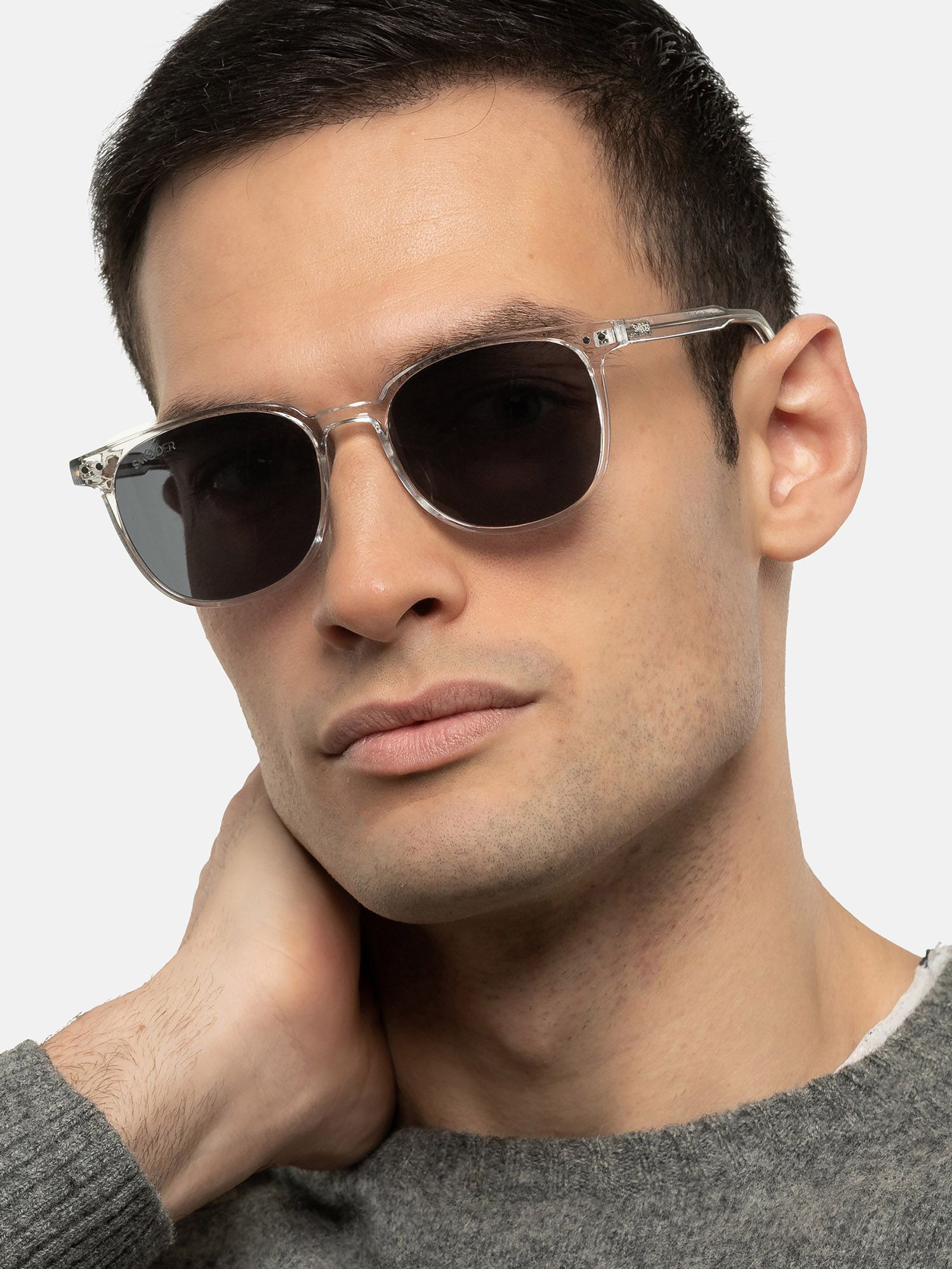 Uomo con occhiali da sole trasparenti, lenti scure. Forma squadrata, montatura leggera. 'Smooder'.