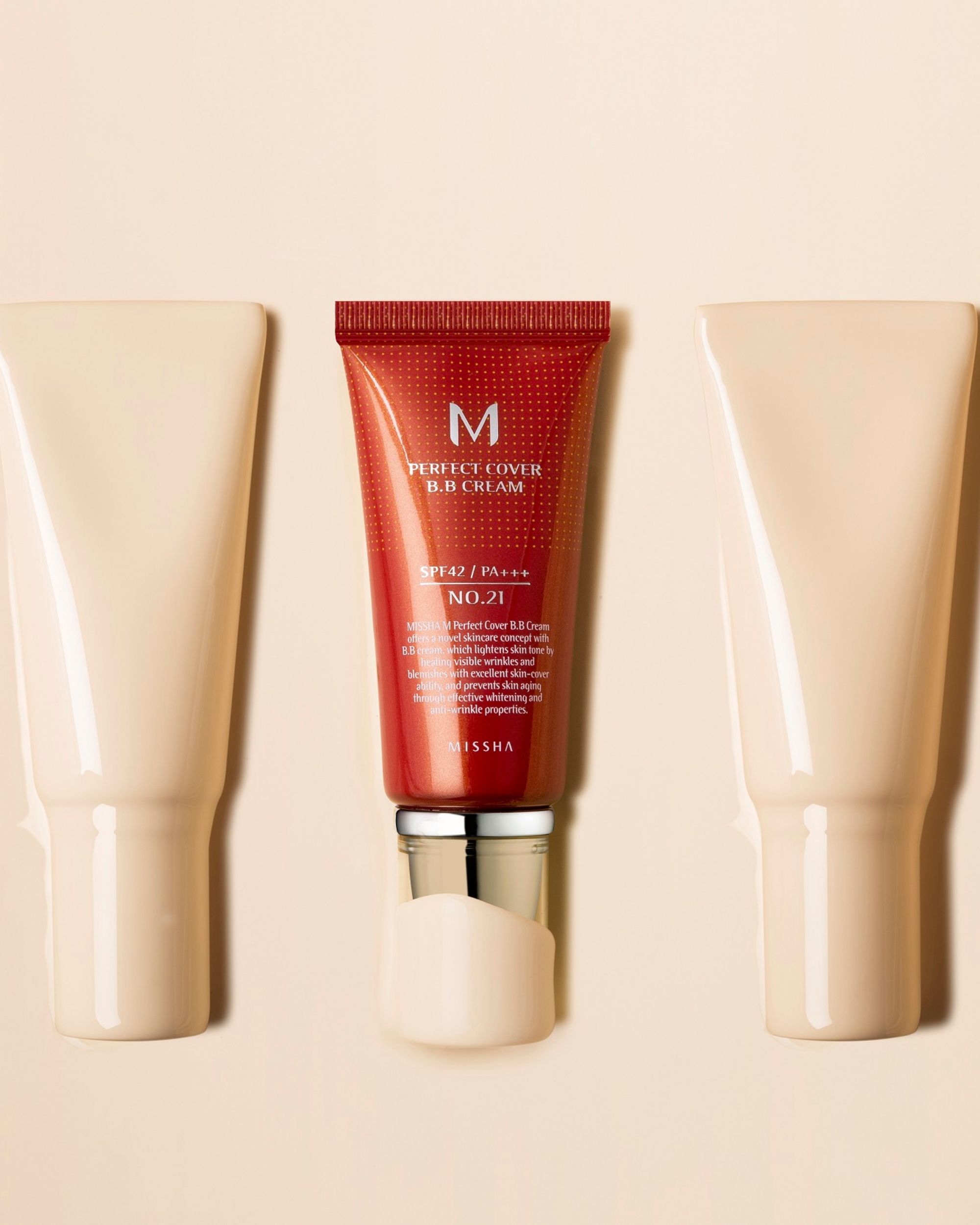 Tubo di BB Cream con testo: Perfect Cover, SPF42 PA+++, MISSHA. Tonalità #21. Circondato da macchie di crema.