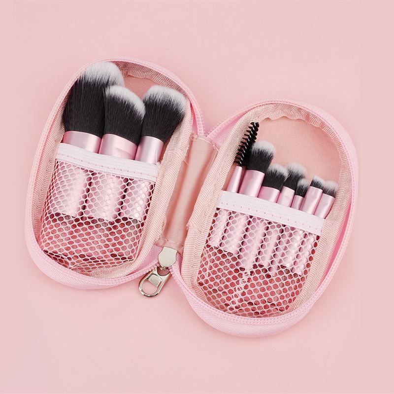 Astuccio cosmetico rosa con cerniera, aperto. Contiene pennelli con manici rosa e setole nere. Scomparti a rete.