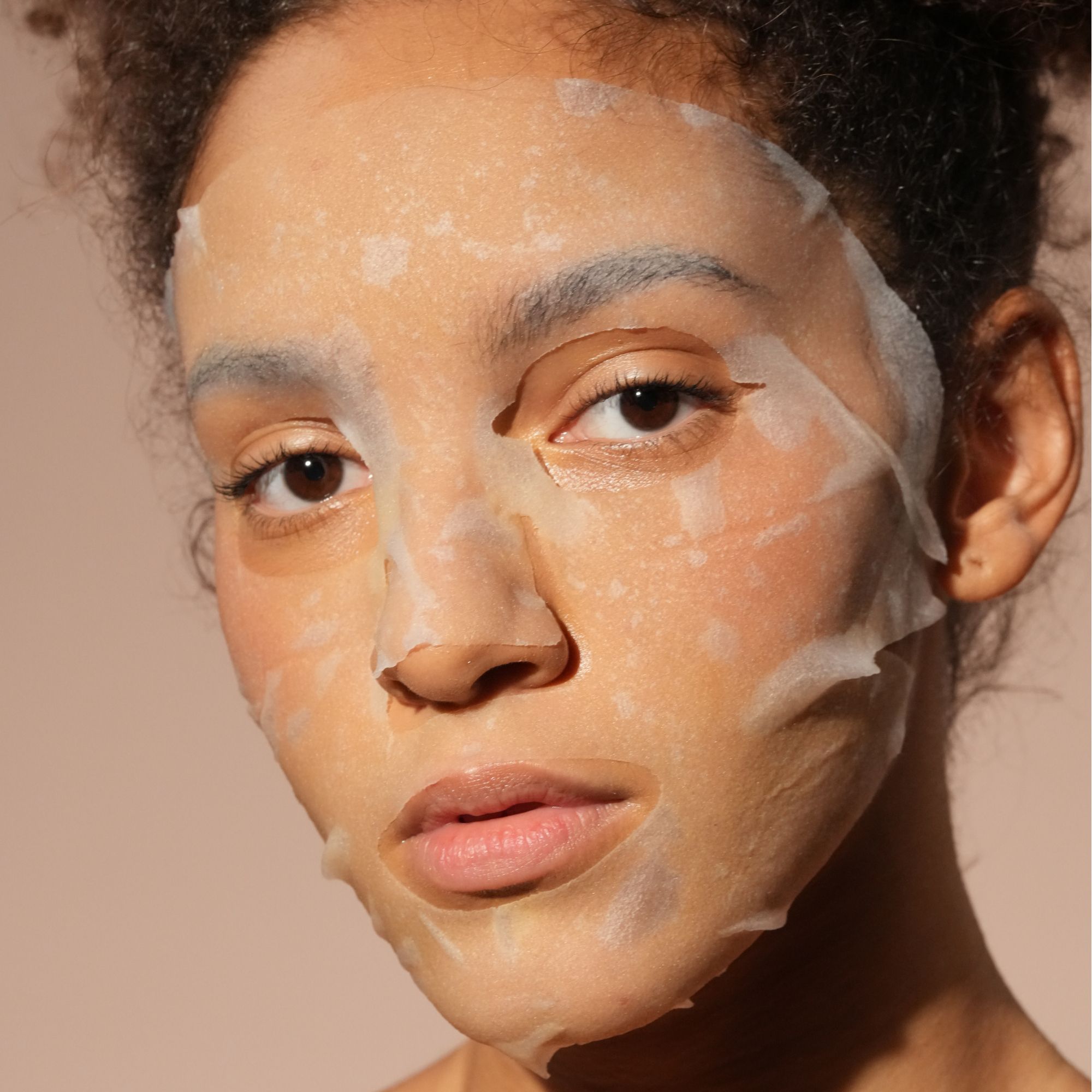 Donna con maschera viso idratante in tessuto a base di collagene.