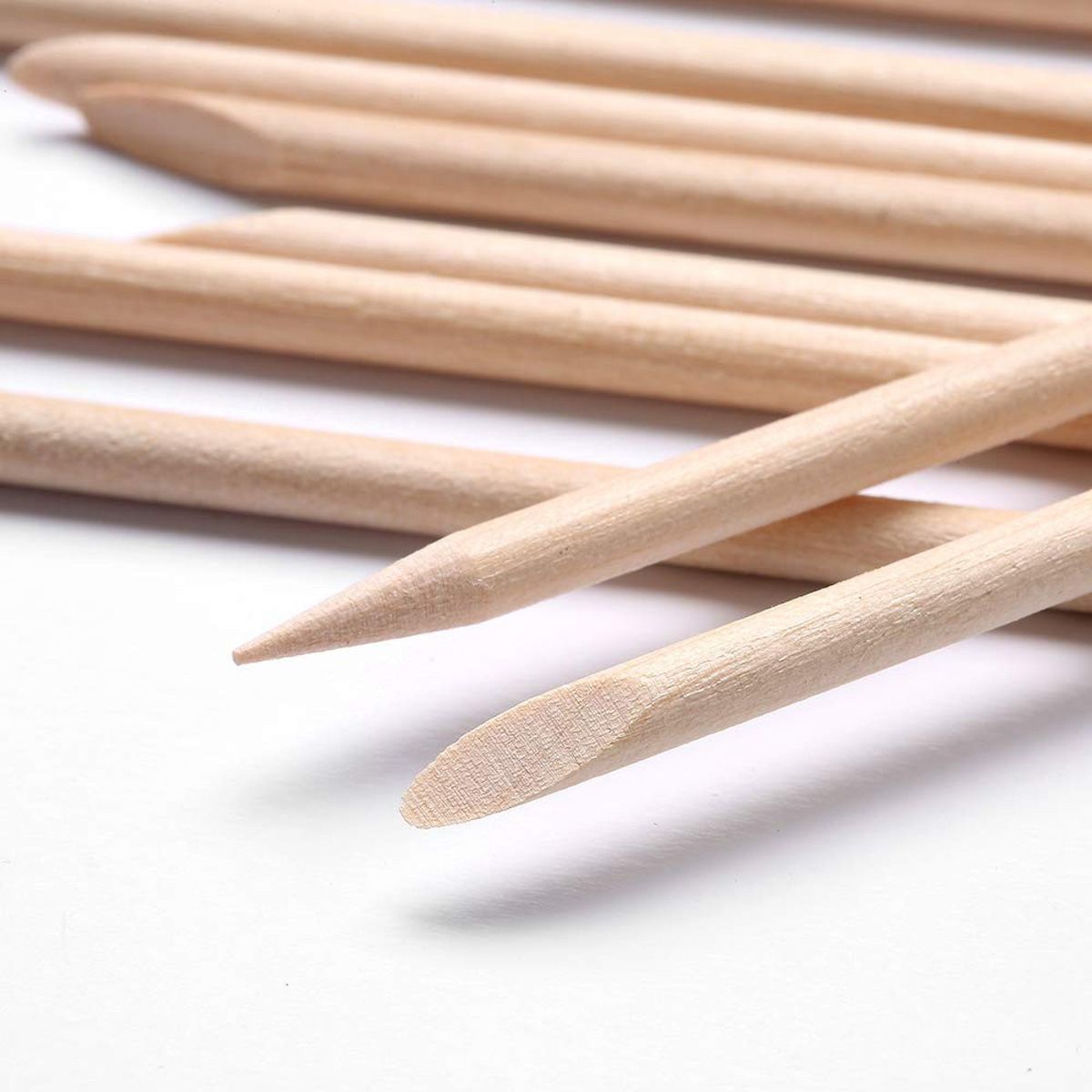Primo piano di bastoncini per manicure. Colore legno, punte appuntite e arrotondate. Diversi bastoncini affiancati.