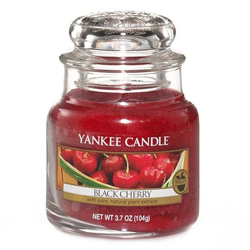 Piccola candela profumata Yankee Candle Black Cherry in vetro con coperchio. Cera rossa, etichetta con immagine di ciliegie.