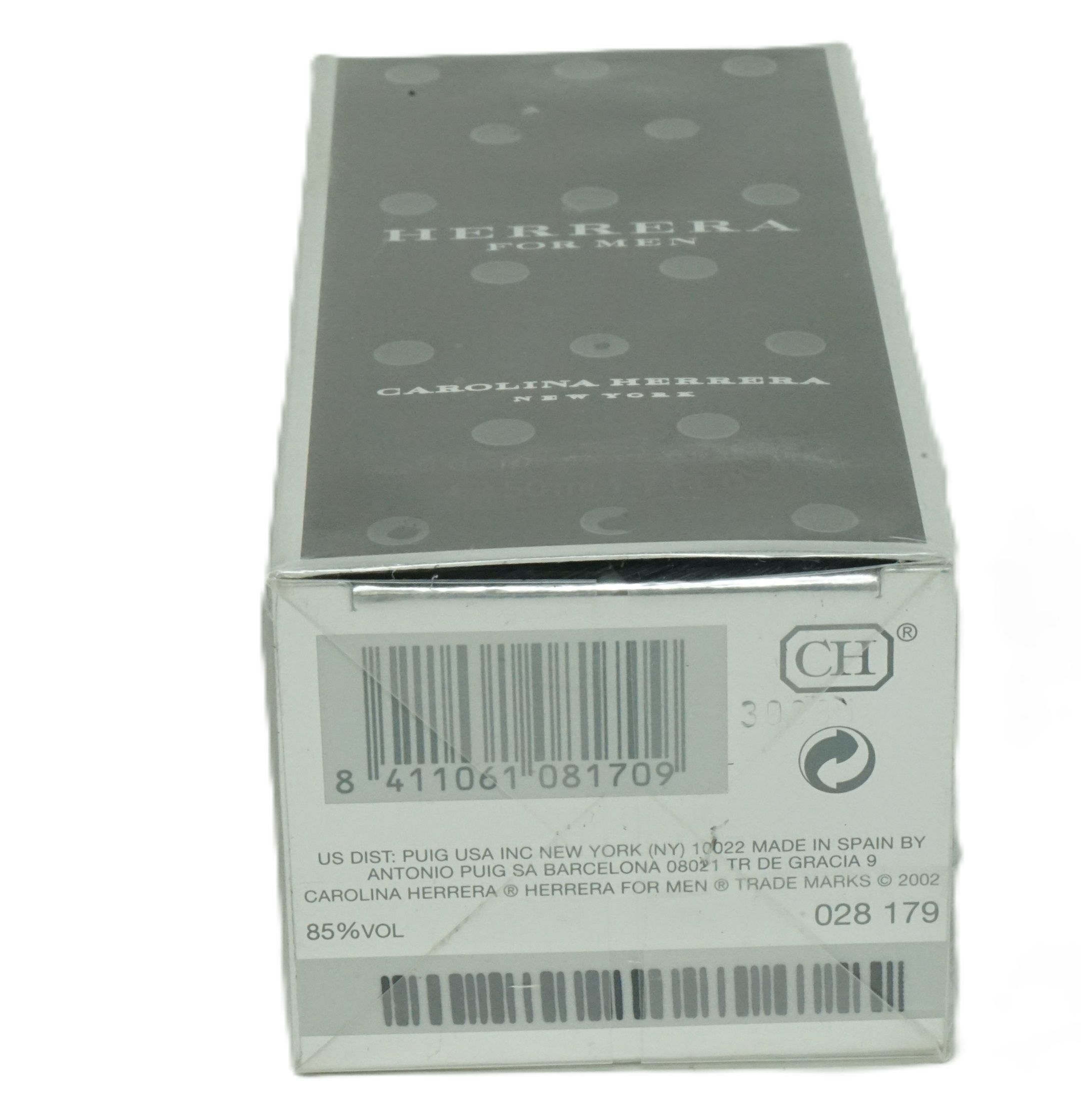 Scatola di cartone con codice a barre, logo CH e testo. Scritta: Herrera For Men, Carolina Herrera New York. 85% Vol.