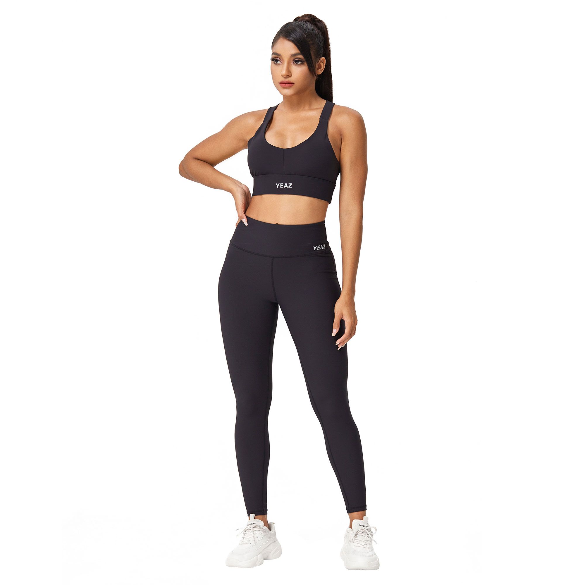Reggiseno sportivo nero e leggings con logo "YEAZ". Una donna indossa l'outfit.