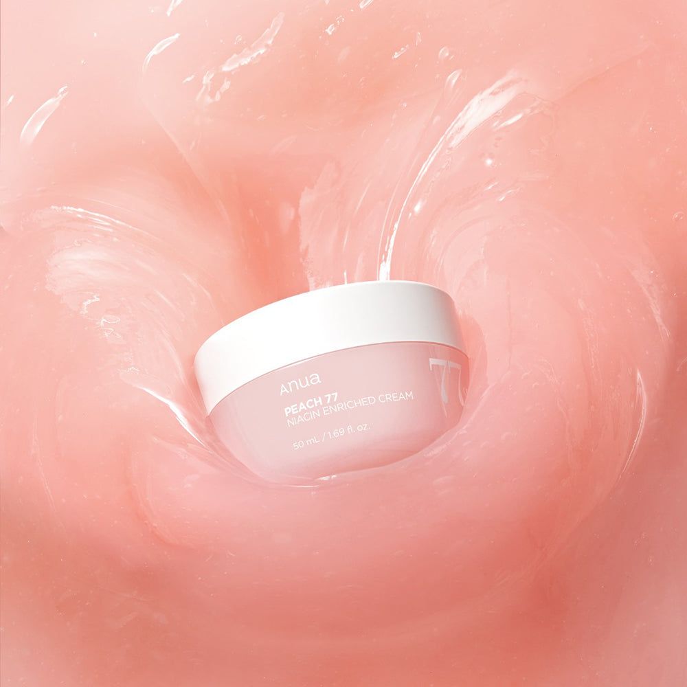 Vaso di crema rosa con coperchio bianco in liquido rosa. Scritta: Anua, PEACH 77, Niacin Enriched Cream, 77%.