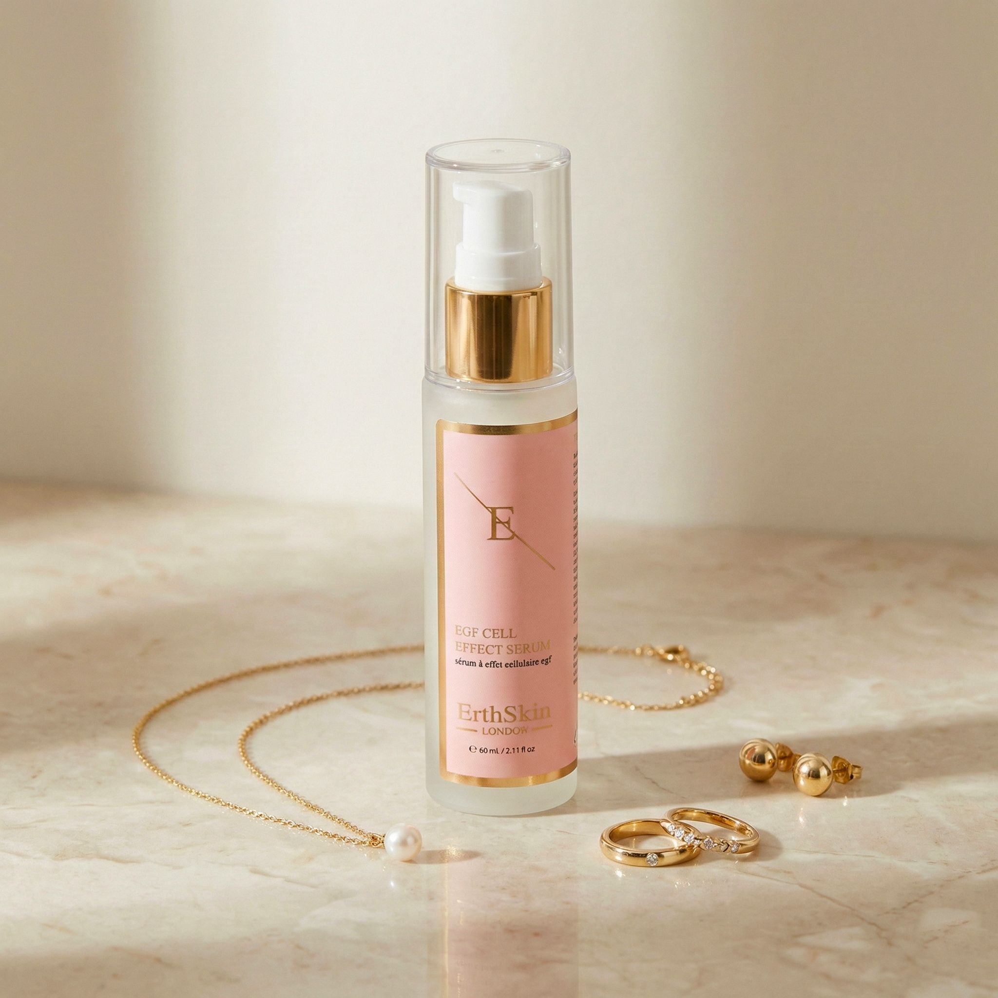 Siero ErthSkin London EGF accanto a gioielli: collana, orecchini e anelli su superficie in marmo.