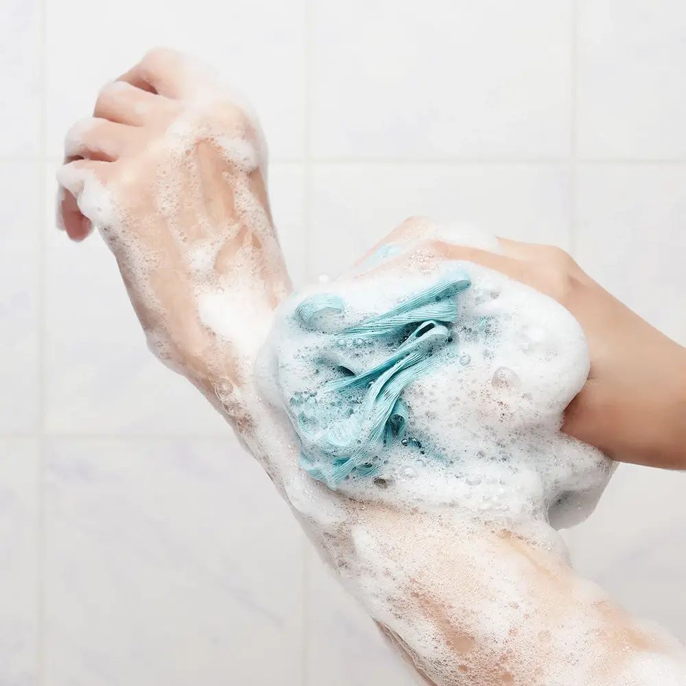 Mani con schiuma e spugna blu. Schiuma che ricopre le mani.