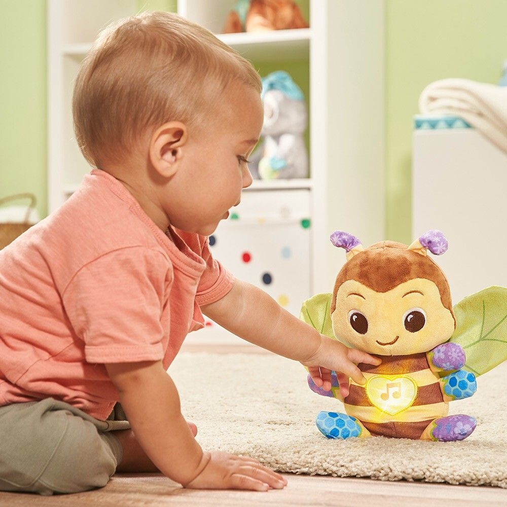 Un bambino gioca con un giocattolo ape di peluche illuminato con un simbolo di nota musicale.