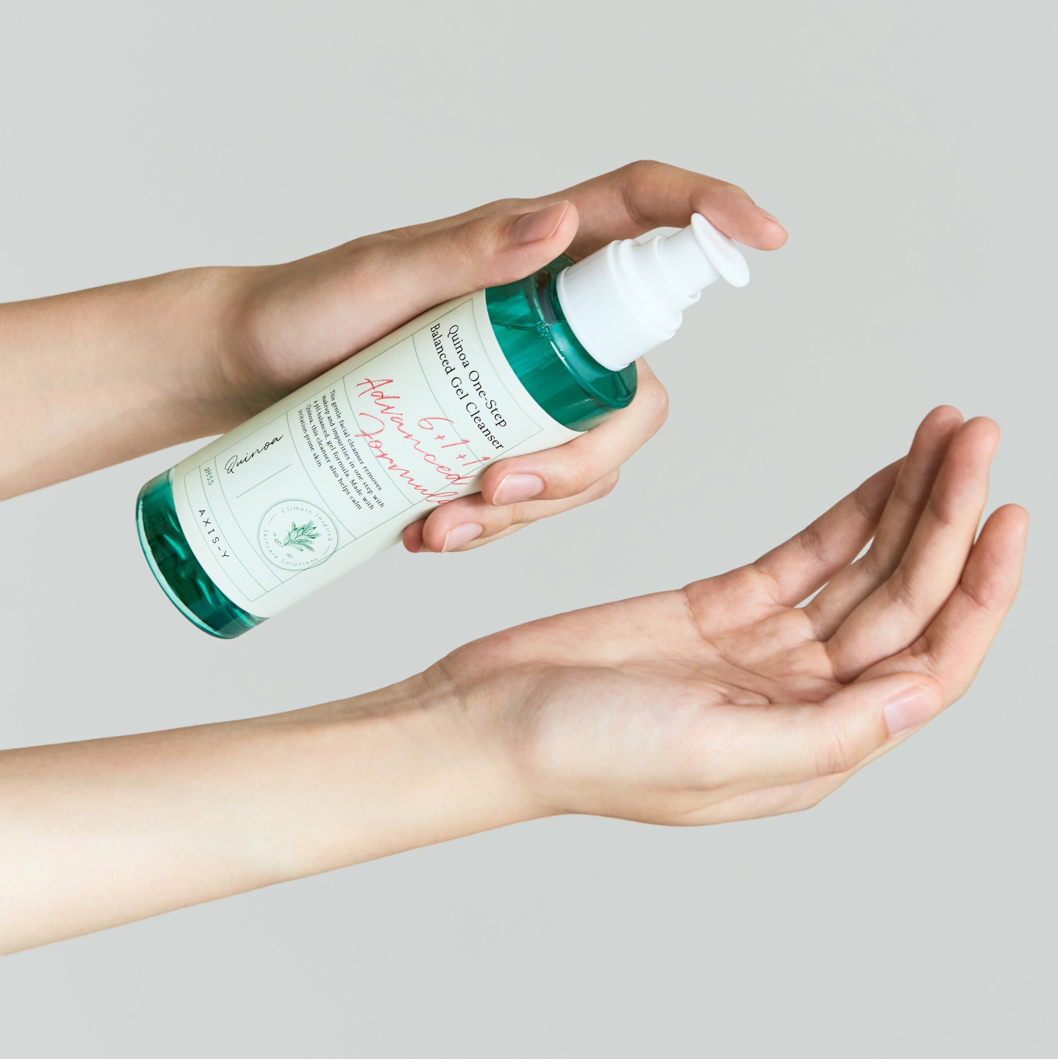 Mani che tengono un flacone. Scritta: Quinoa One-Step Balanced Gel Cleanser, 6+1+1 Advanced Formula. Flacone premuto nel palmo.