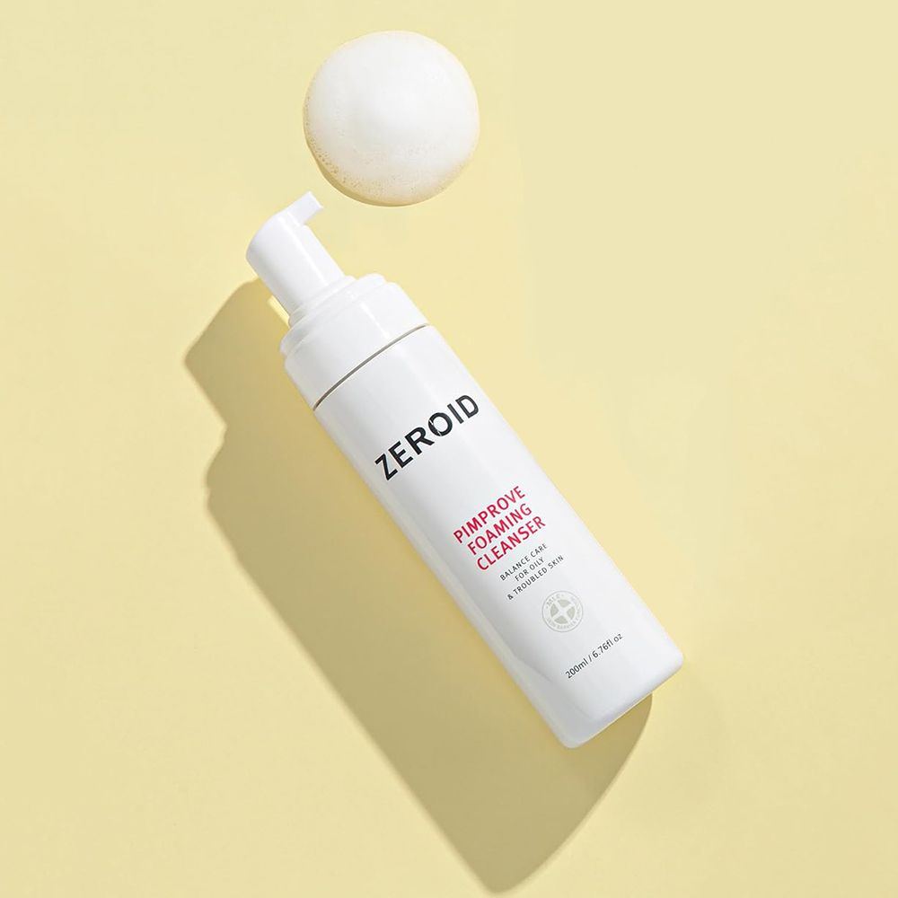 Flacone bianco ZEROID Pimprove Foaming Cleanser con pompa. Nome prodotto e testo. Su sfondo giallo. Sfera di schiuma.