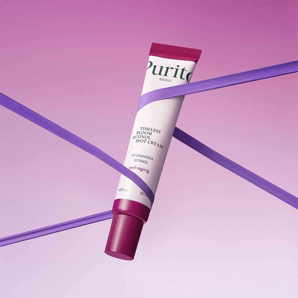 Tubo di crema PURITO Timeless Bloom Retinol Spot Cream, avvolto da nastri viola.