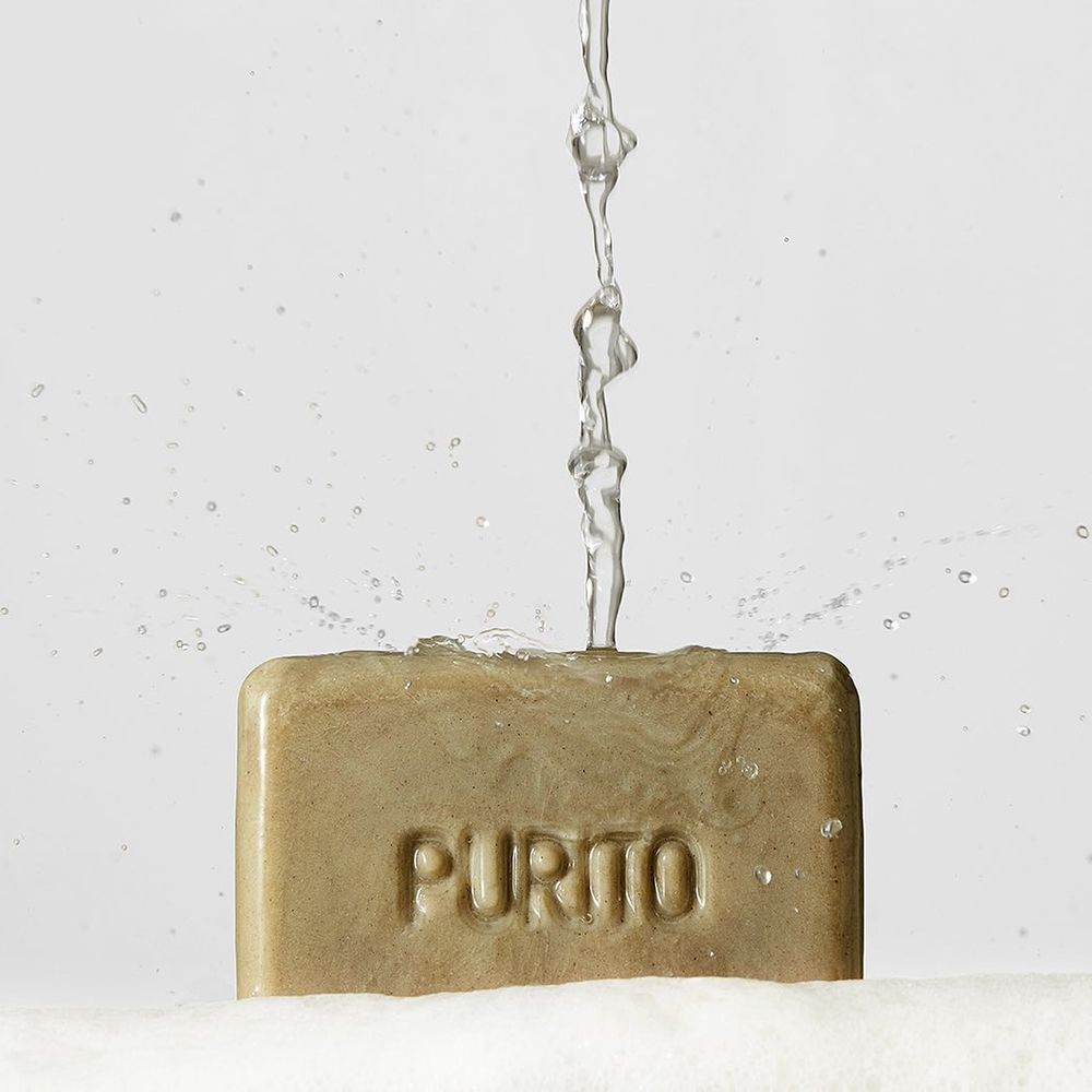 Sapone sotto l'acqua corrente. Sul sapone è scritto « PURITO ».