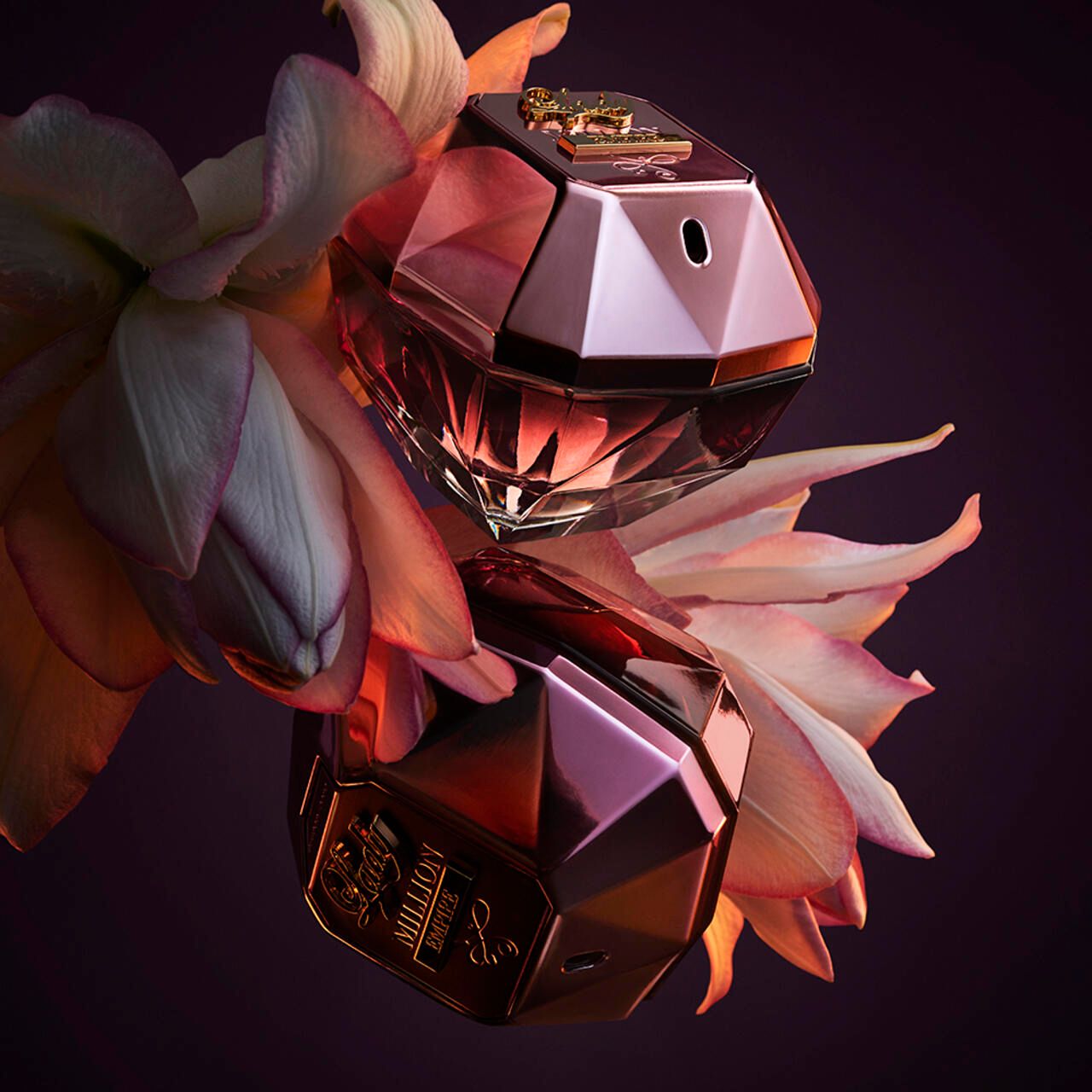 Due flaconi rosa con tappo dorato. Scritta: Lady Million Empire. Posizionati su fiori.