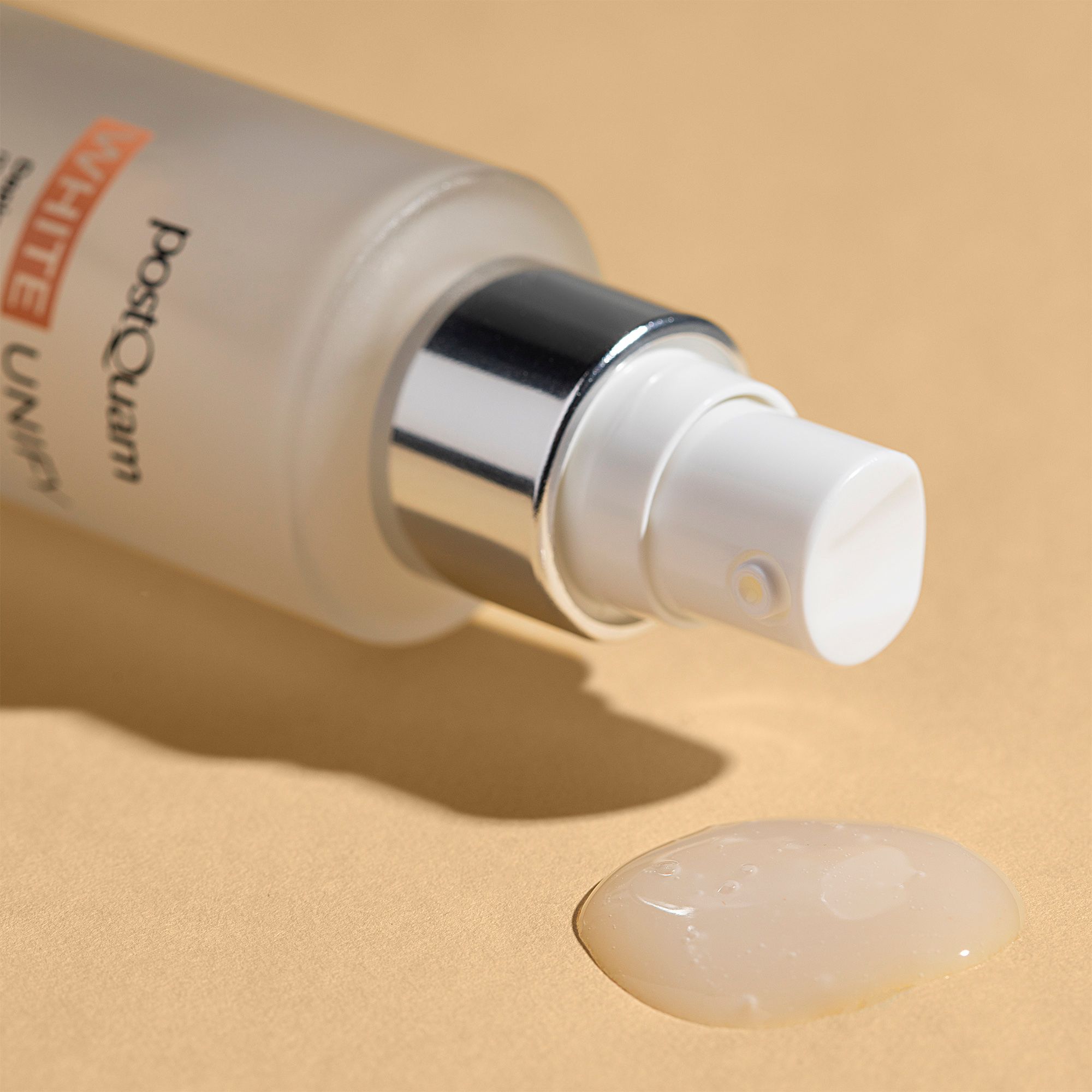 Flacone di siero con vaporizzatore e goccia di siero. Scritta: PostQuam, White Unify. Il siero è incolore.