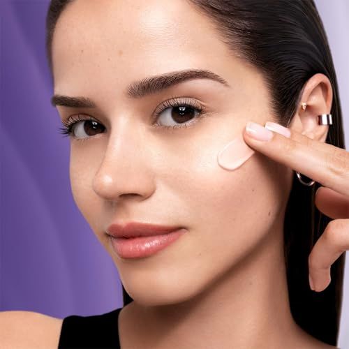 Donna applica crema sulla pelle. Prodotto non riconoscibile. Sfondo viola.