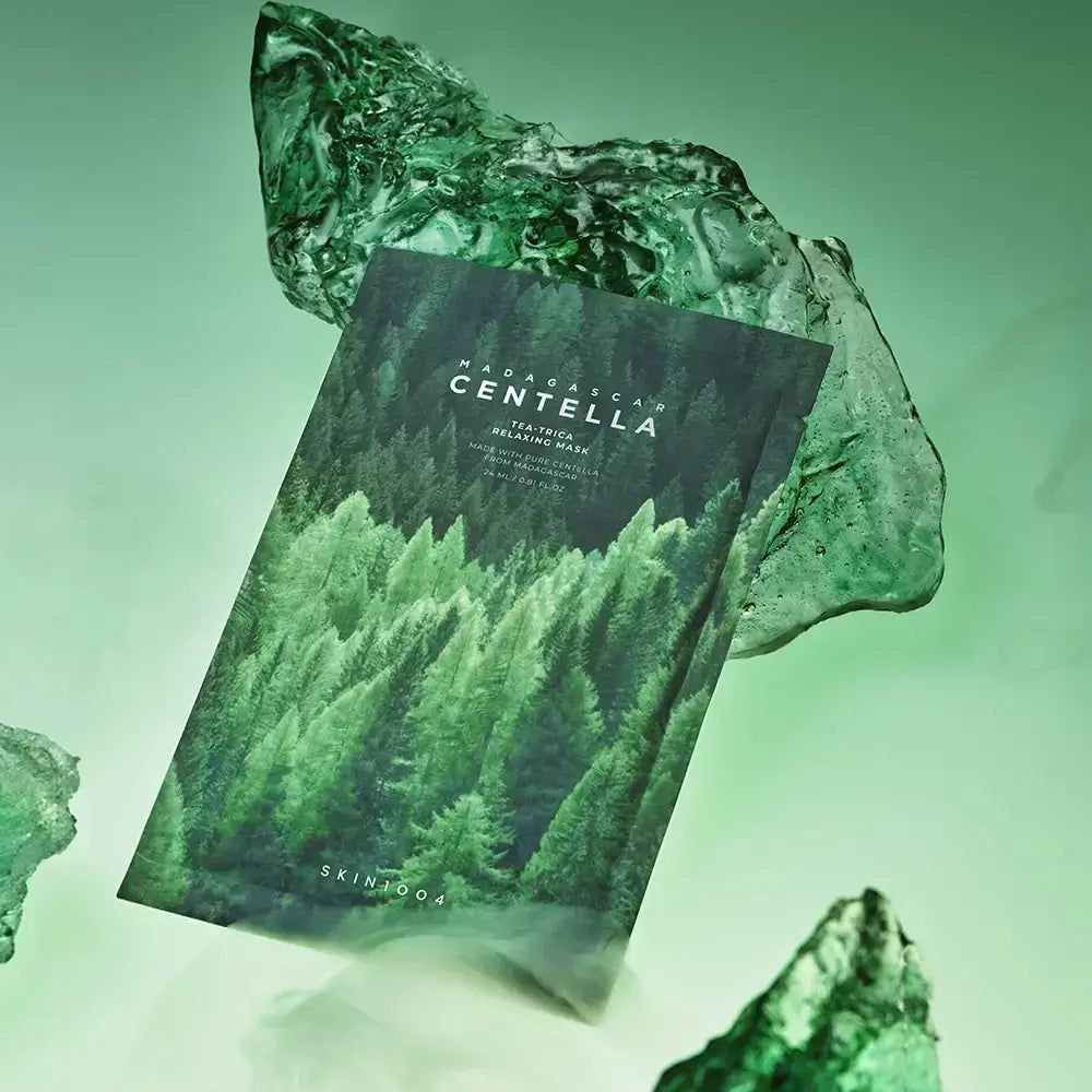 Confezione maschera viso con motivo foresta e scritta MADAGASCAR CENTELLA. Tra frammenti di vetro verde.