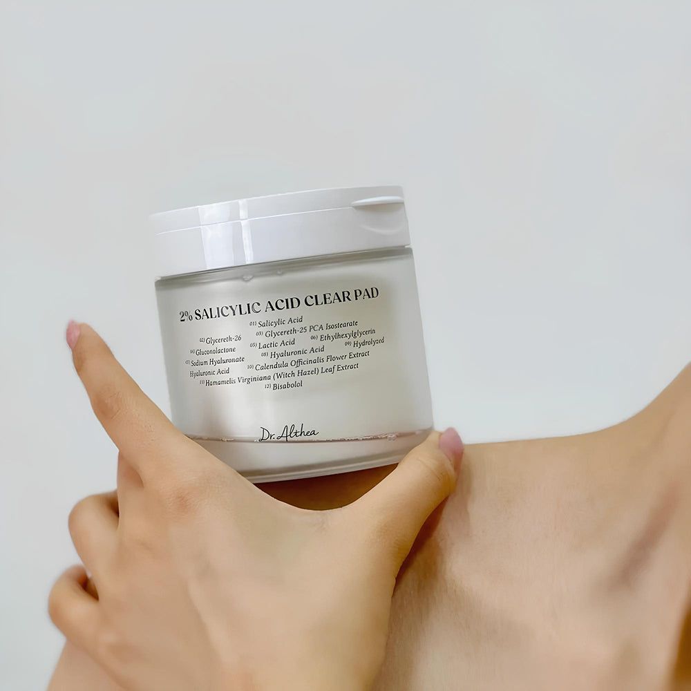 Dr. Althea 2% Salicylic Acid Clear Pad in un contenitore di vetro tenuto da una mano.
