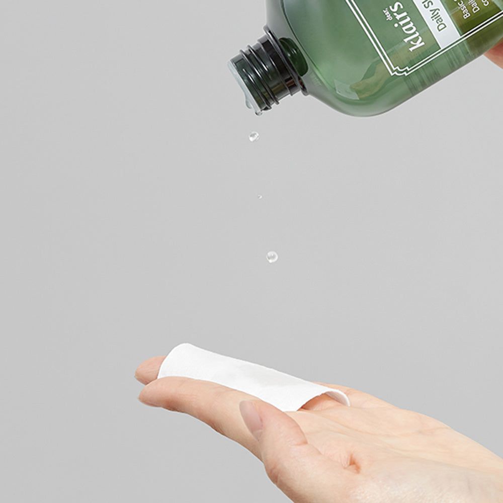 Flacone verde, liquido versato su un dischetto di cotone. Scritta: Daily Skin Softening Water.