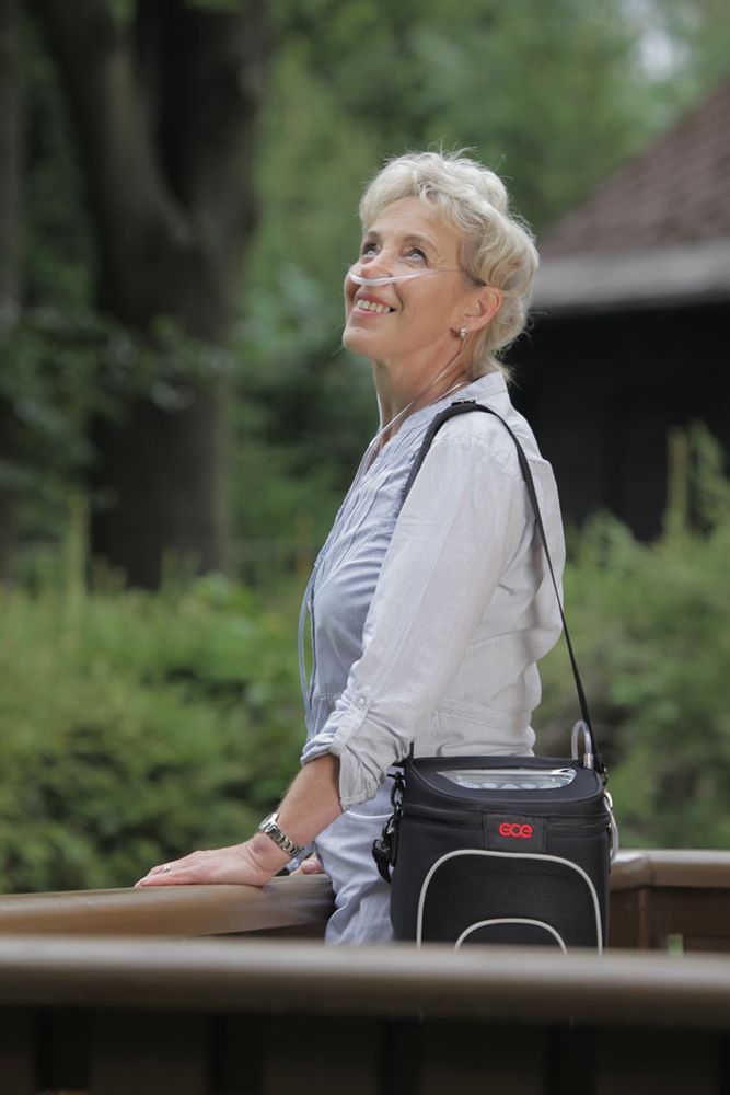 Donna con concentratore di ossigeno GCE Zen-O. Borsa nera con tracolla. Cannula nasale.