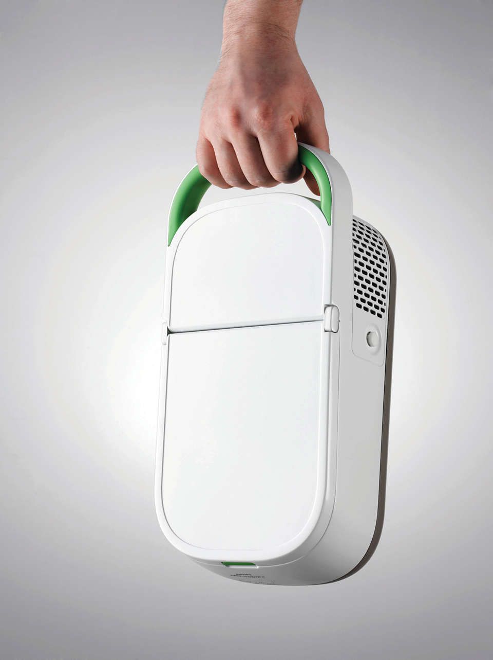 Dispositivo medico bianco con maniglia verde, tenuto in mano. Philips Respironics InnoSpire Deluxe.