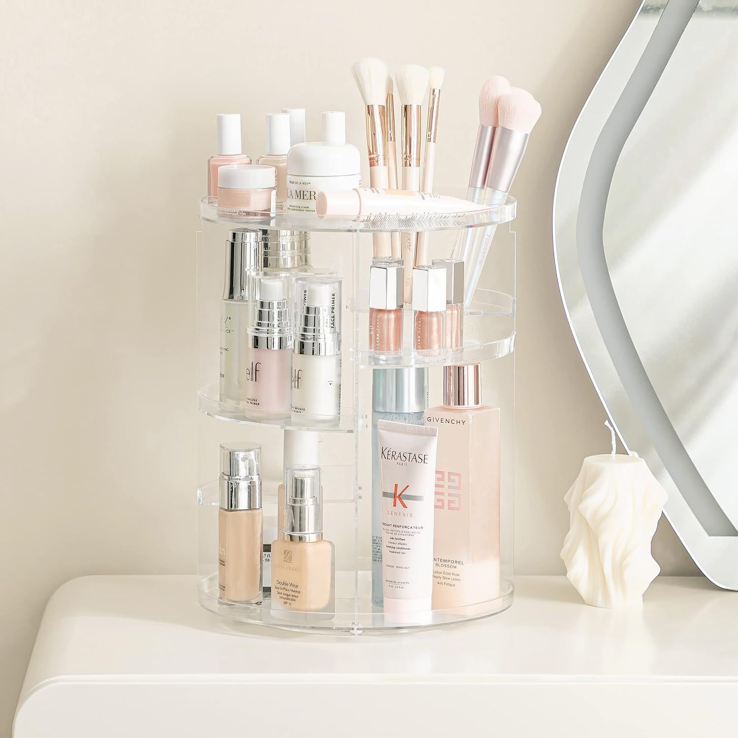 Organizzatore cosmetico rotante in acrilico trasparente a più livelli, riempito con cosmetici e pennelli.