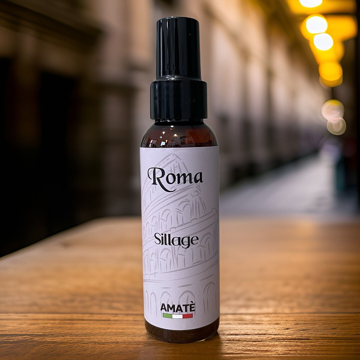 Flacone marrone con vaporizzatore nero su legno. Scritta "Roma Sillage" e "AMATÈ".