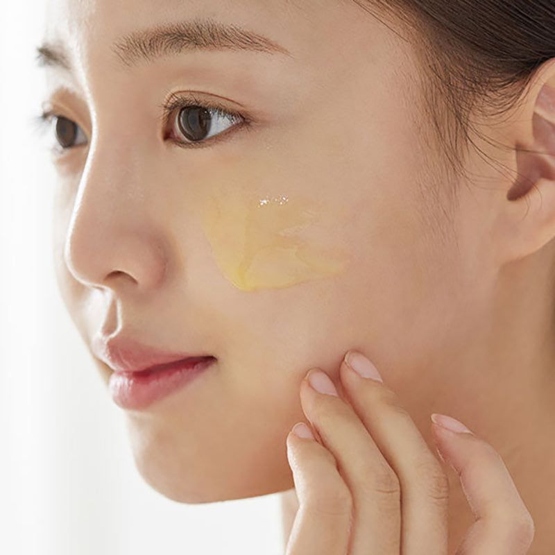 Donna applica siero. Liquido giallo sulla pelle. Viso di profilo.