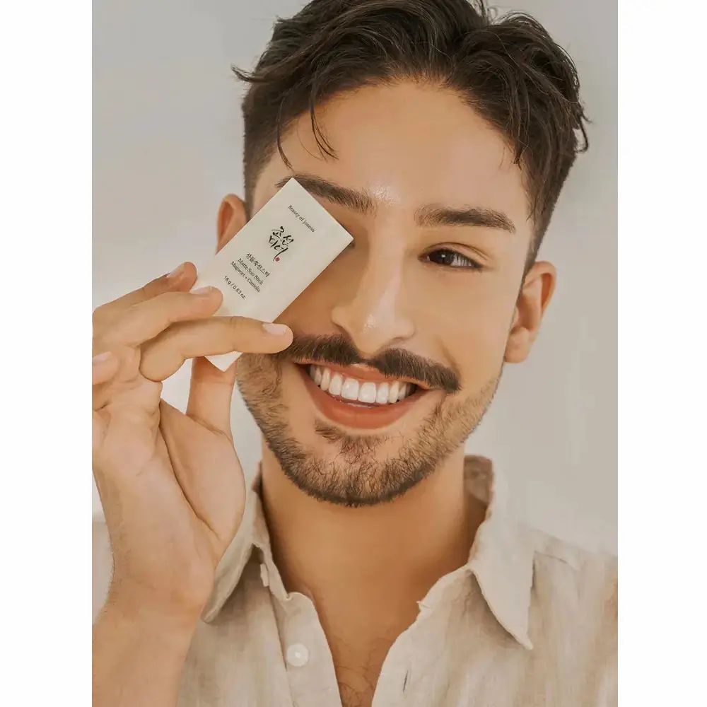 Uomo tiene in mano uno stick solare bianco. Espressione: sorridente.