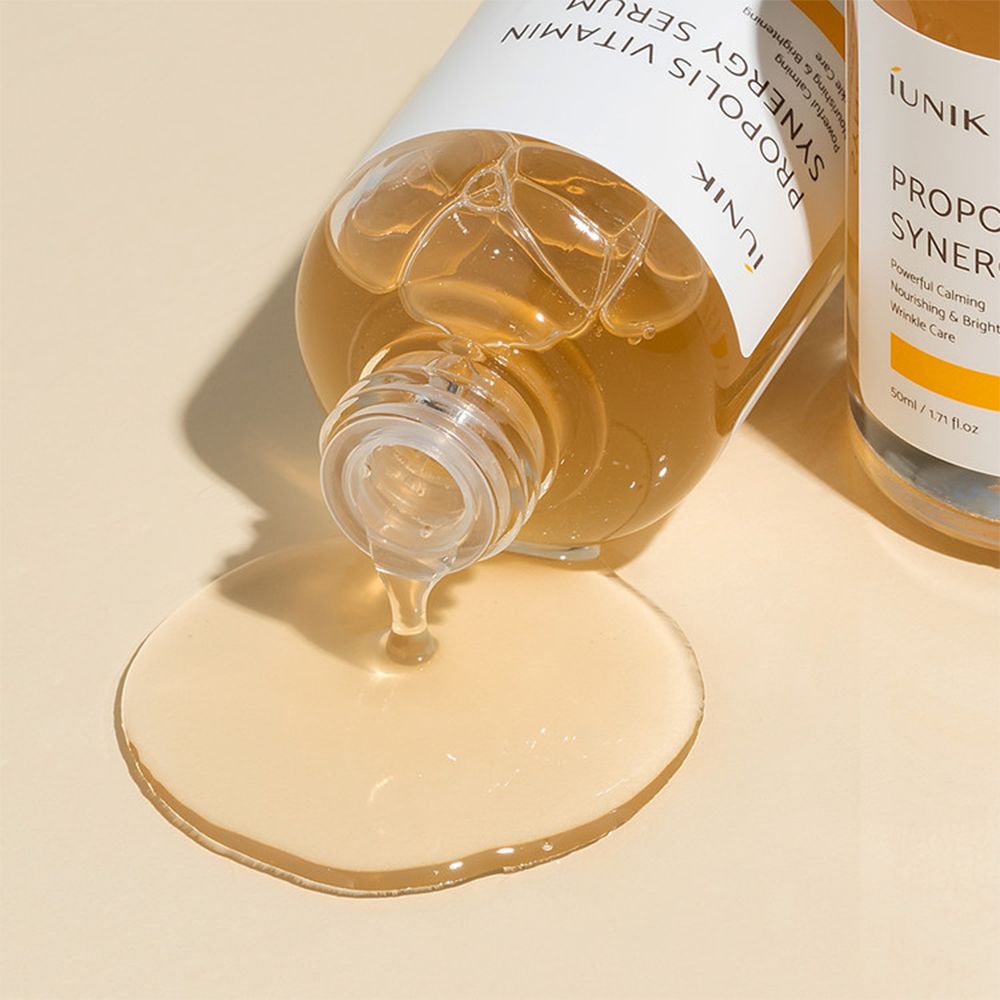 Il Siero Sinergia Propoli Vitamina iUNIK cola da una bottiglia. Il siero è giallo dorato.