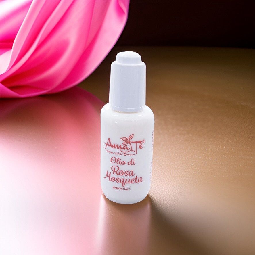 Flacone bianco con scritta rossa: Amatè Olio di Rosa Mosqueta. Made in Italy. Su sfondo dorato.