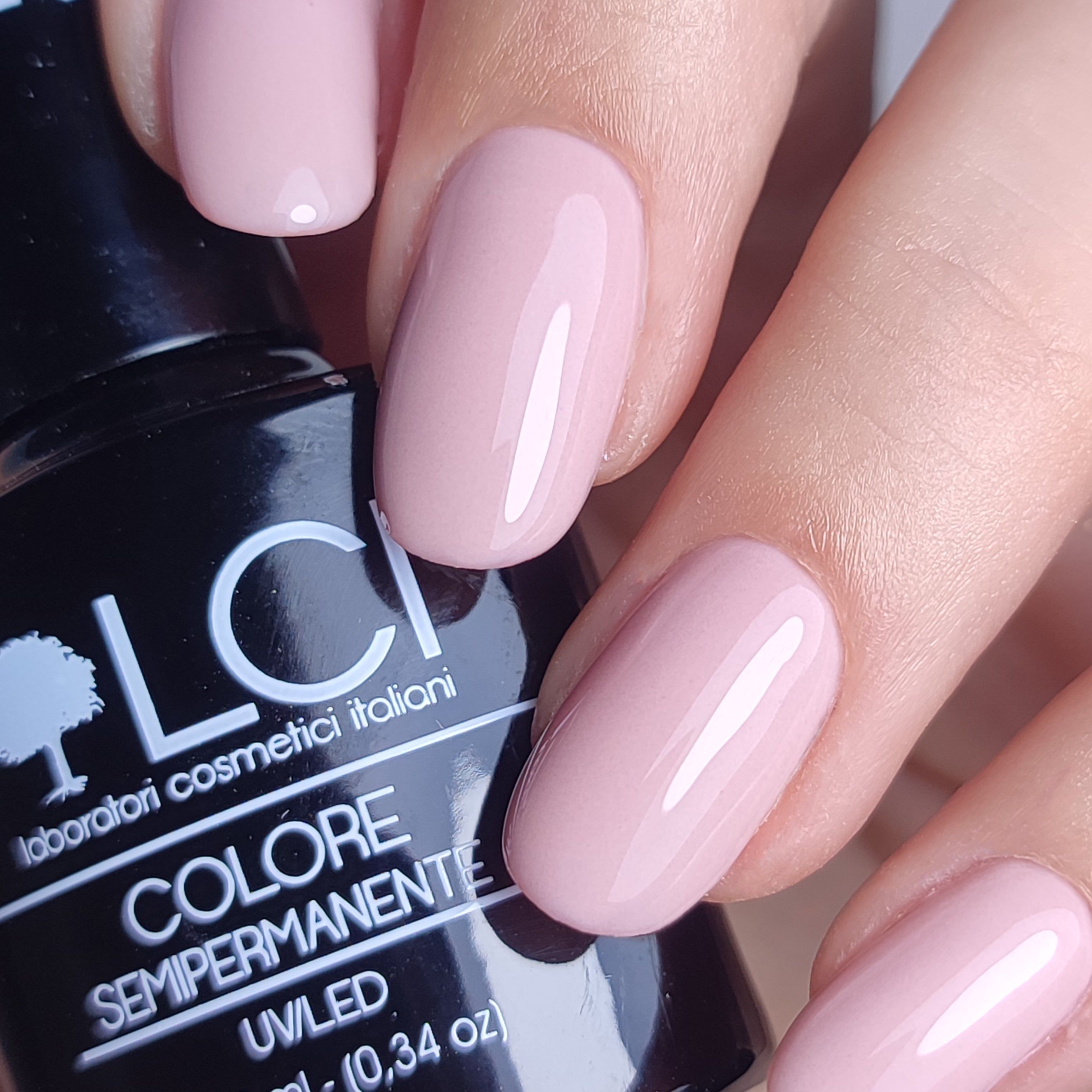 Mano con unghie smaltate rosa. Flacone con scritta LCI, COLORE SEMIPERMANENTE.