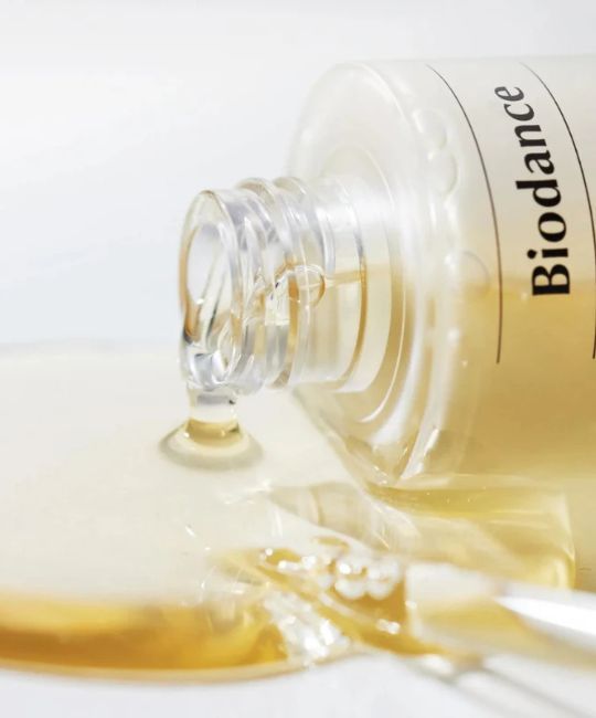 Siero BIODANCE Skin Glow Vital Ampoule che cola da un flaconcino di vetro. Liquido giallo chiaro.
