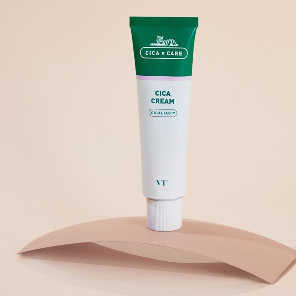 Tubo di Cica Cream. Tubo verde e bianco con tappo verde. Scritta: Cica Cream, CICALIAO. Marchio: VT. Appoggiato su una superficie ondulata.