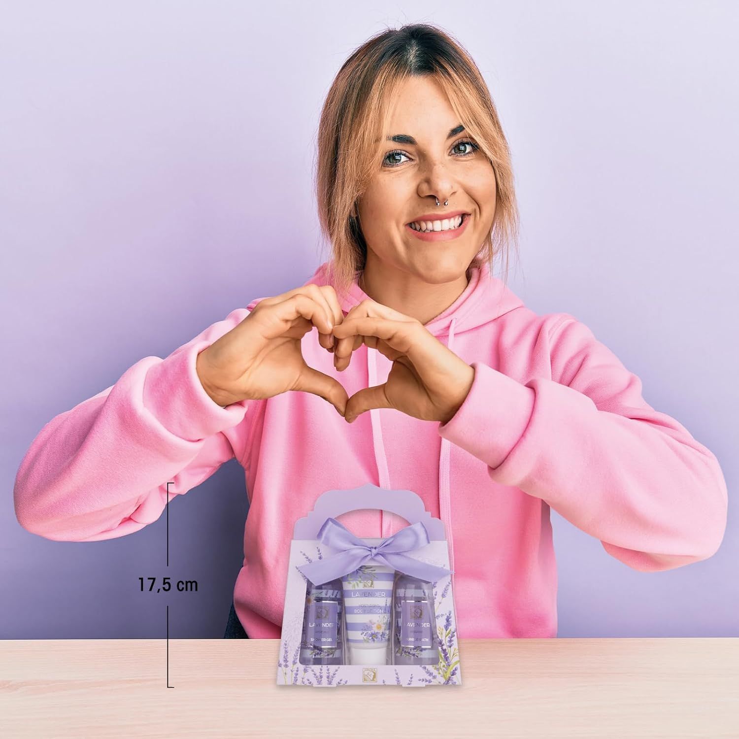 Donna forma un cuore con le mani sopra la confezione regalo. Confezione regalo con gel doccia, lozione e bagno schiuma. 17,5 cm.