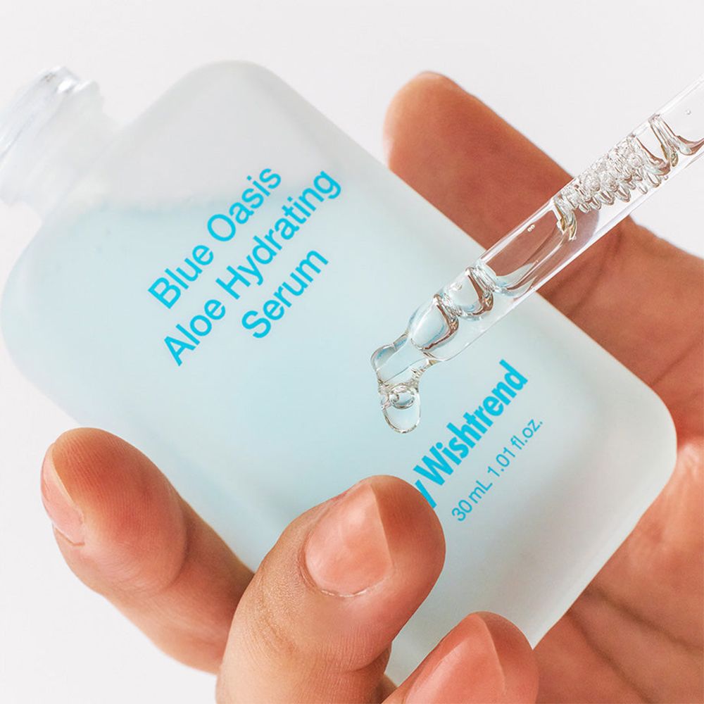 Mano che tiene un flacone di siero con pipetta. Scritta: Blue Oasis Aloe Hydrating Serum, By Wishtrend.