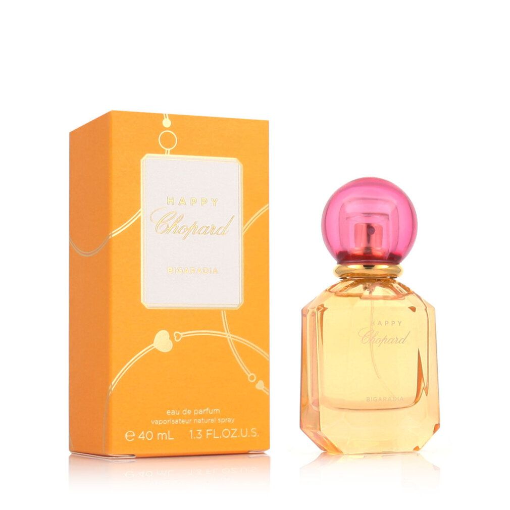Flacone di profumo e confezione. Flacone con tappo rosa, liquido giallo. Confezione arancione con etichetta bianca.