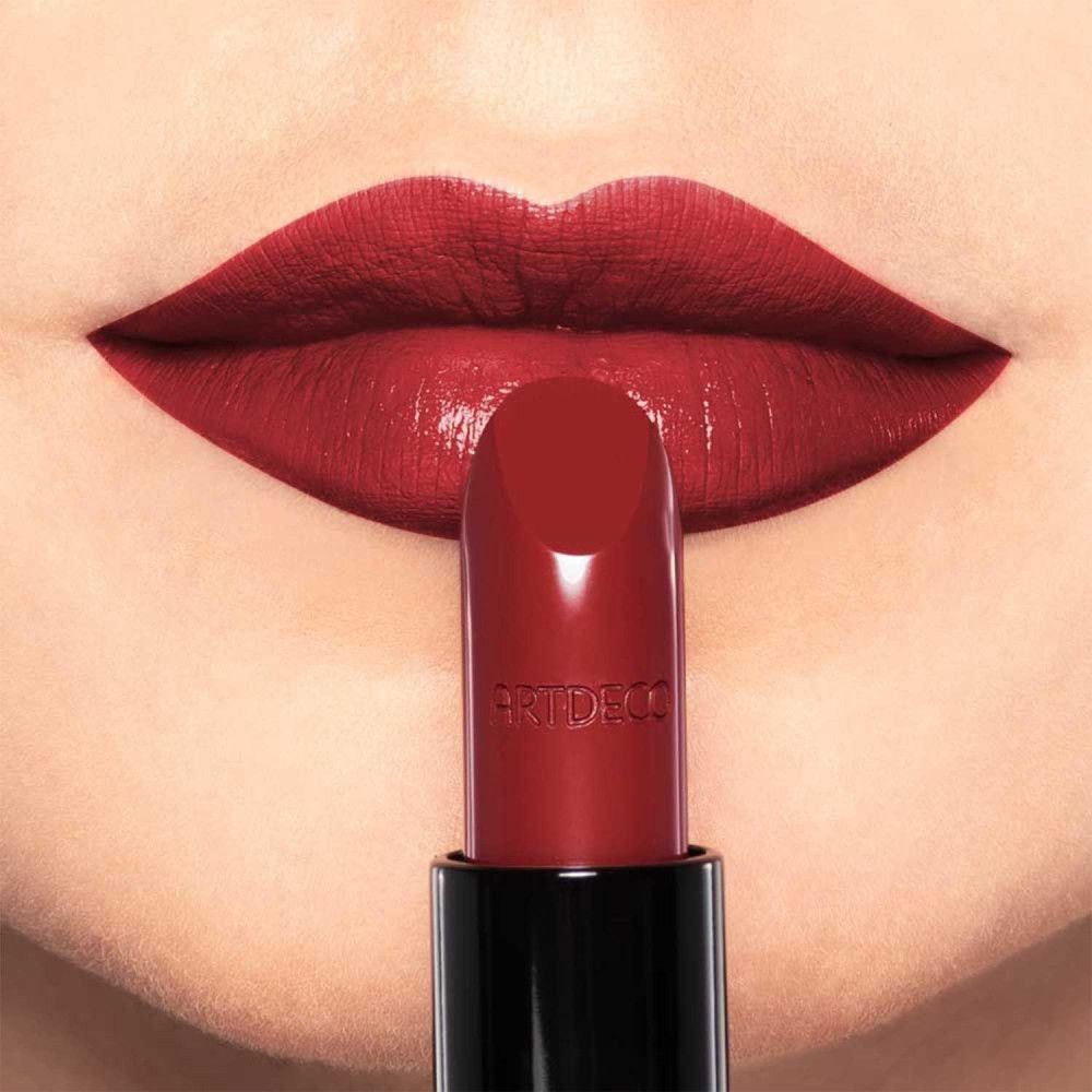 Rossetto rosso davanti a labbra rosse. Sul rossetto c'è scritto "ARTDECO".