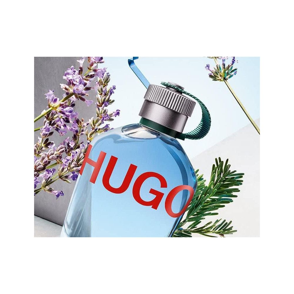 Flacone di profumo Hugo Boss azzurro con scritta HUGO rossa. Tappo argentato, anello verde. Lavanda e rami verdi.