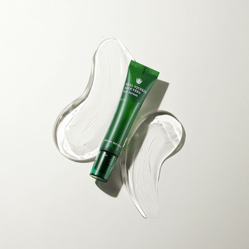 Tubo verde REAL SQUEEZE ALOE VERA Eye Serum, circondato da due tracce di gel trasparente. Sfondo bianco.
