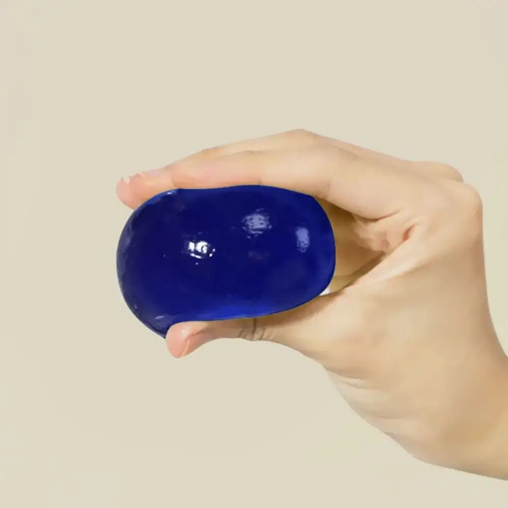 Sfera ovale blu tenuta in mano. Sfondo chiaro e neutro.