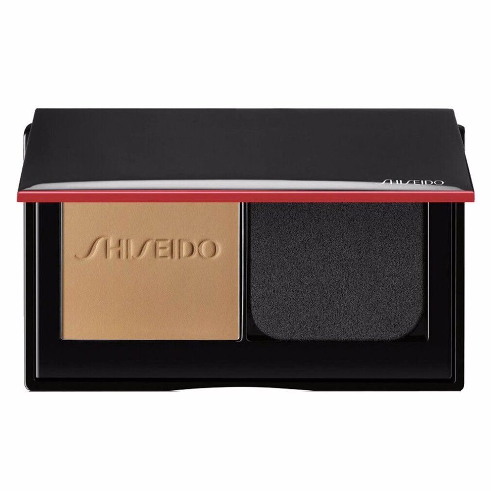 Cipria compatta aperta con polvere e spugna. Cornice nera, accento rosso. Logo Shiseido.