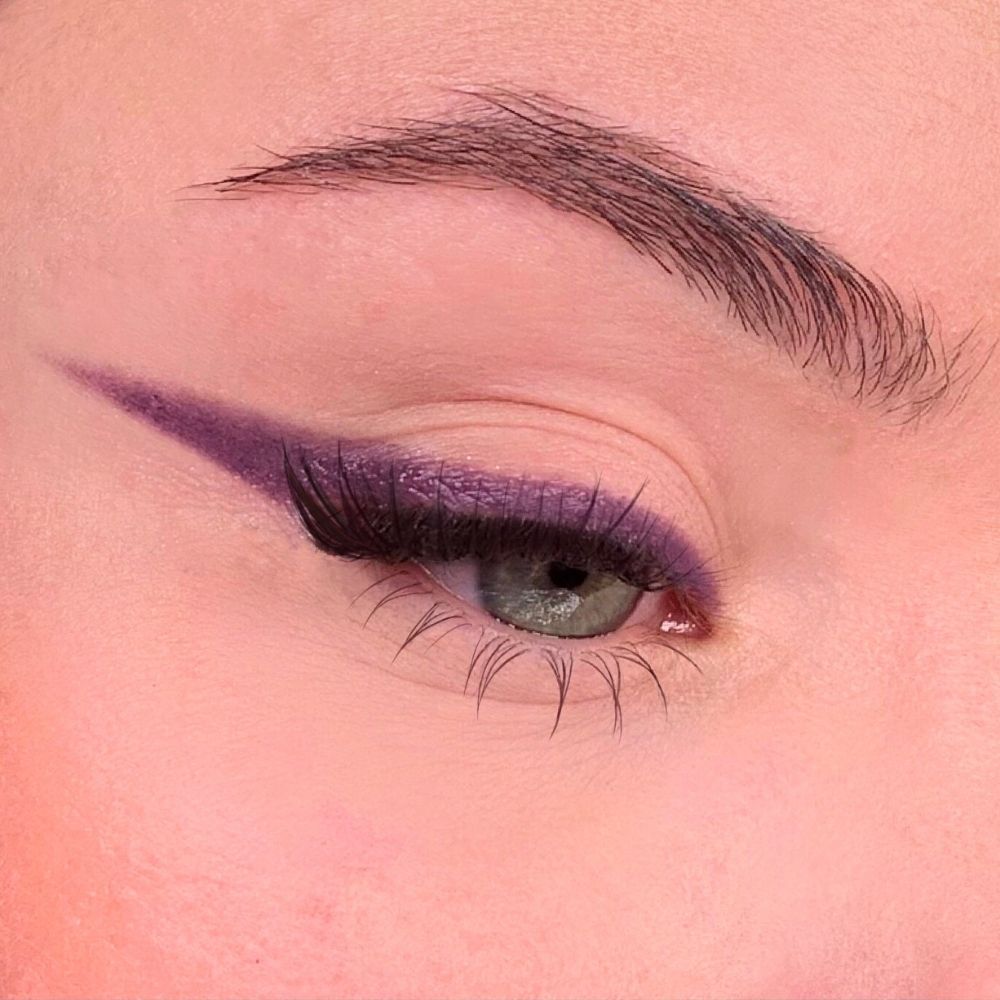 Occhio con eyeliner viola. Palpebra con eyeliner viola. Sopracciglio e ciglia visibili.